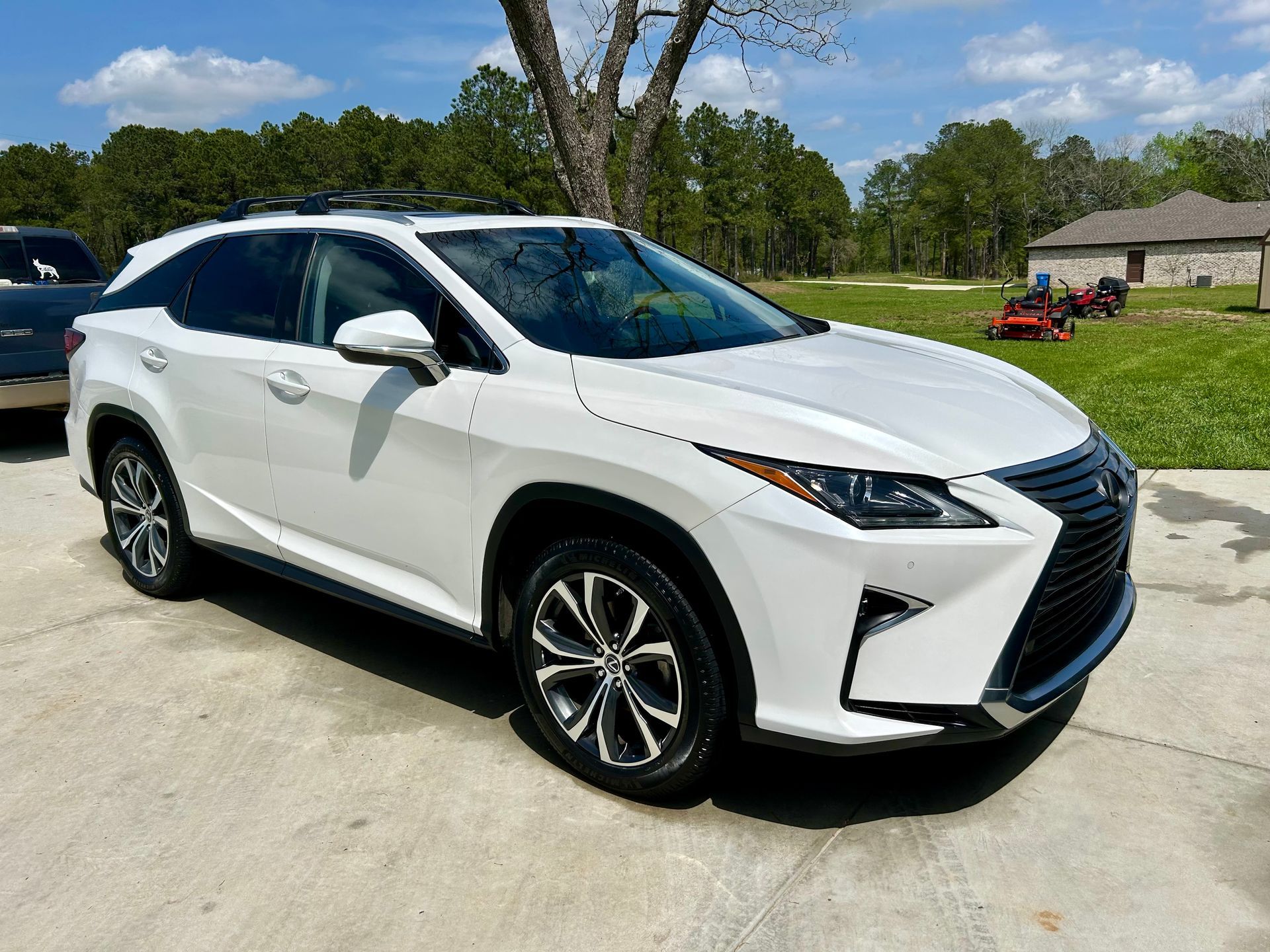 White Lexus SUV parked on a concrete surface, sunny day.