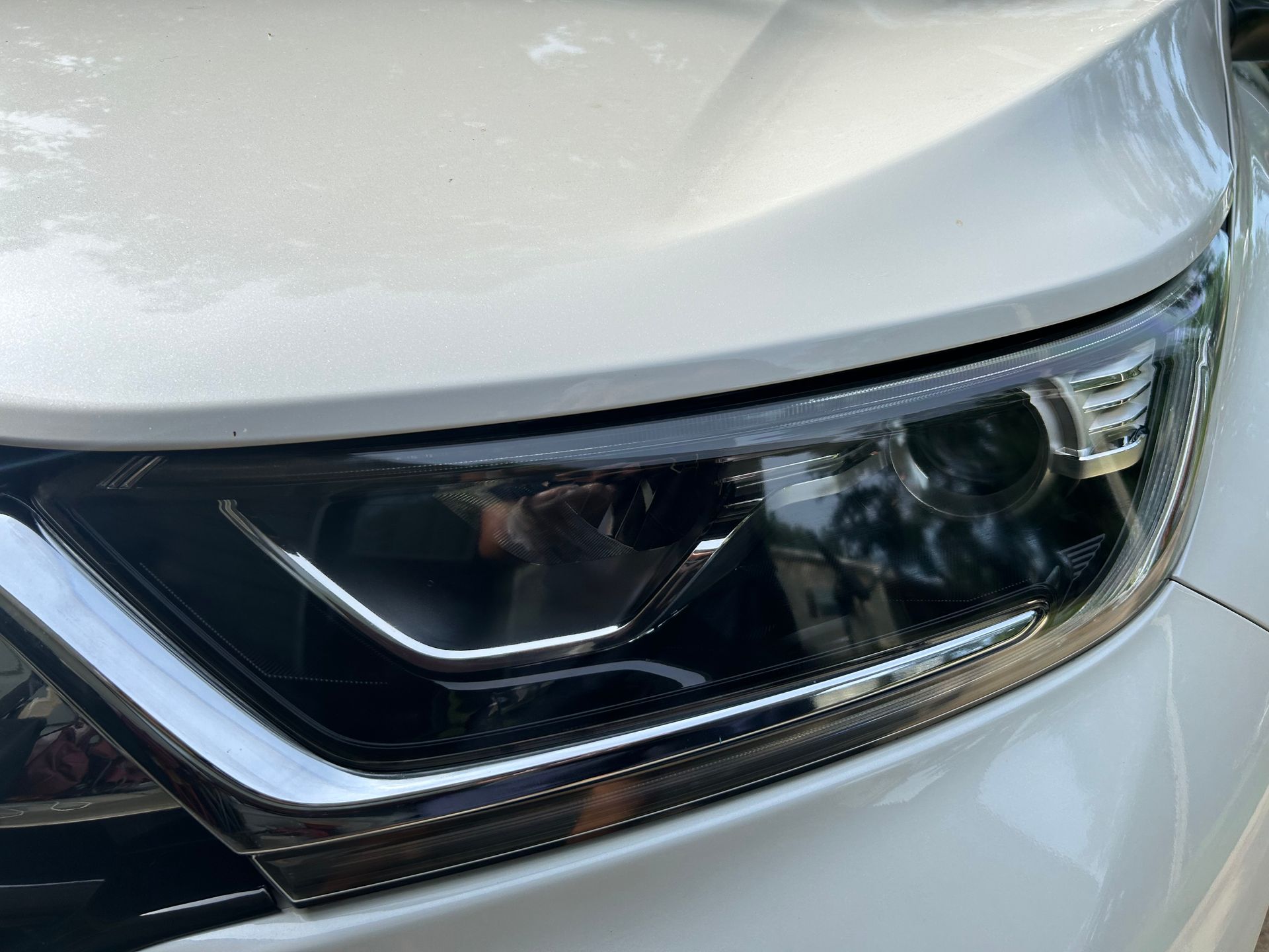 Close-up of a white car's headlight; black trim and chrome detail.