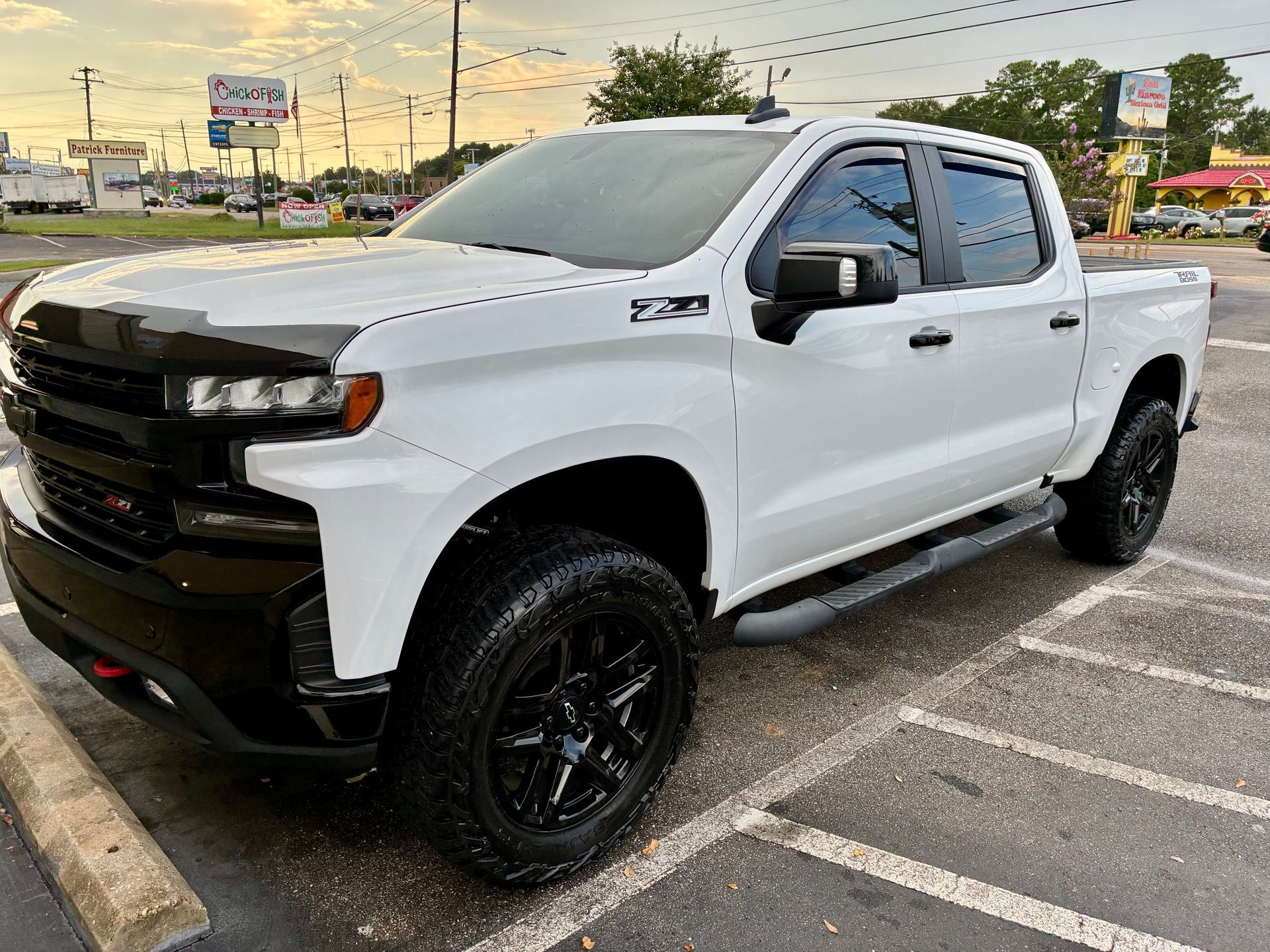 White Chevrolet Silverado truck with black accents, parked on asphalt.