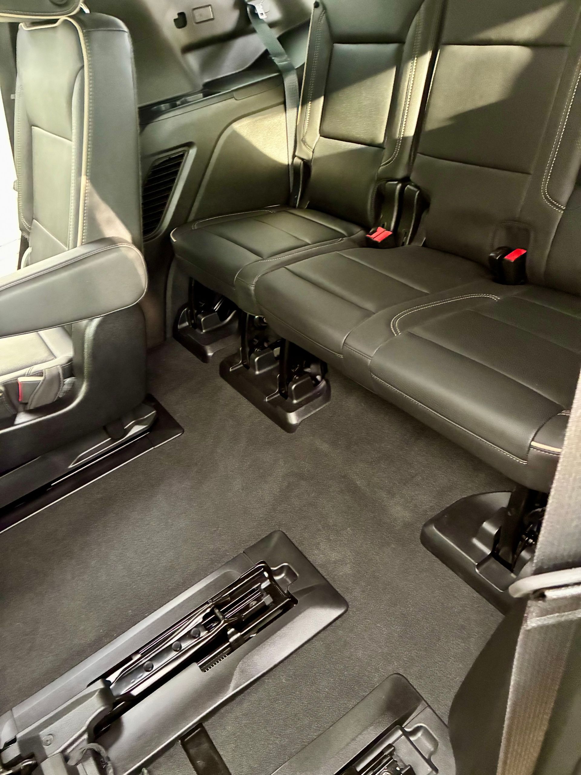 Interior view of a vehicle with dark gray leather seats, seatbelt, and carpeted floor.