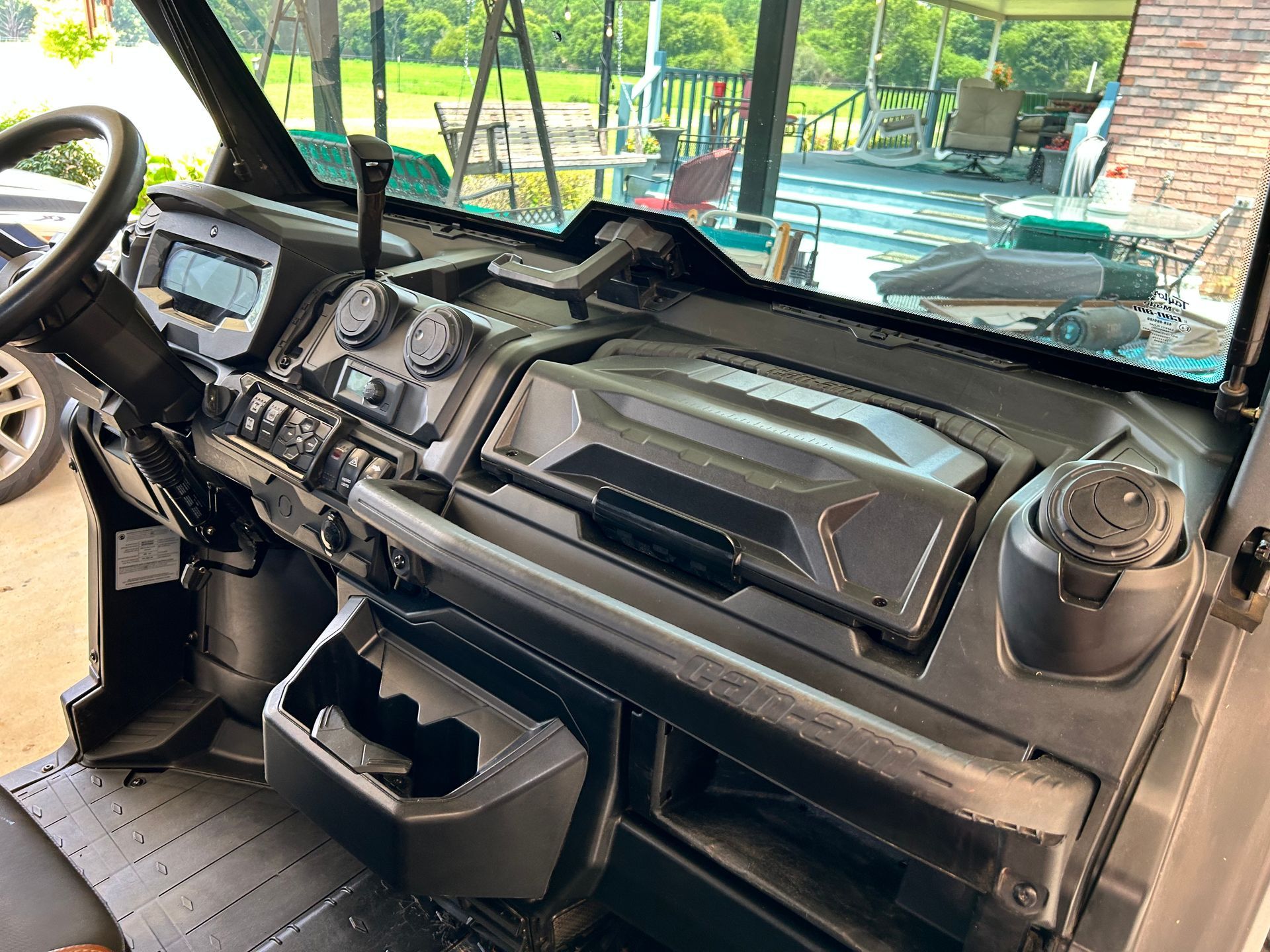 Black UTV interior with dashboard, gauges, and windshield, parked outdoors.