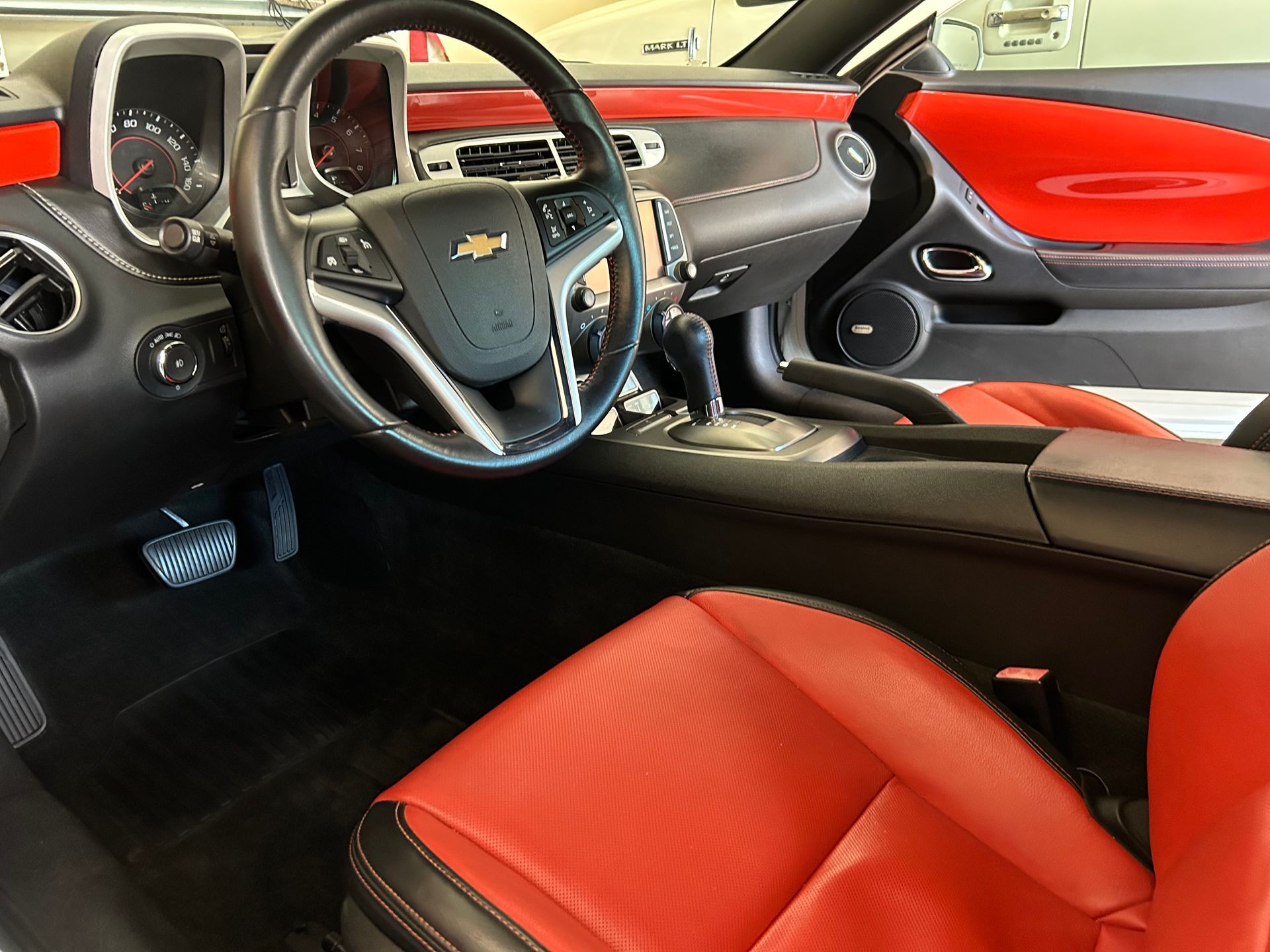Interior view of a red and black Chevrolet Camaro with the steering wheel, seats, and dashboard visible.