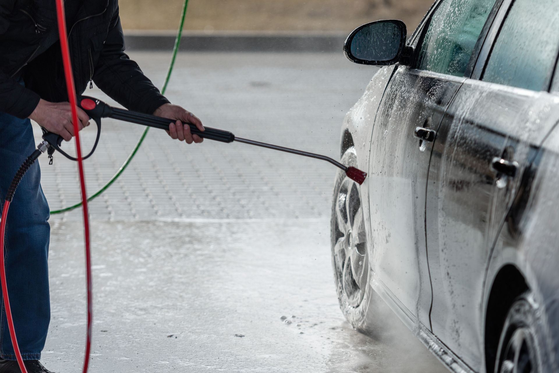 Person washing a dark blue car with a soapy orange cloth.