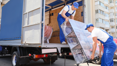 Two men are loading a couch into a truck.