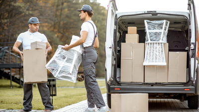 Two movers are loading boxes into a van.
