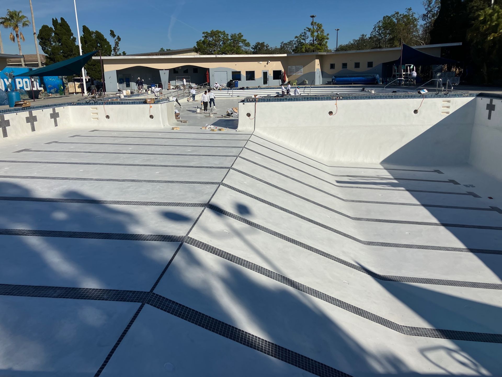 A swimming pool is being remodeled with a building in the background that says sunny pool