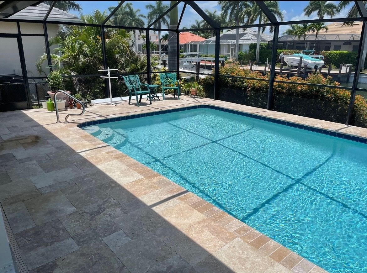 A large swimming pool is surrounded by a screened in area