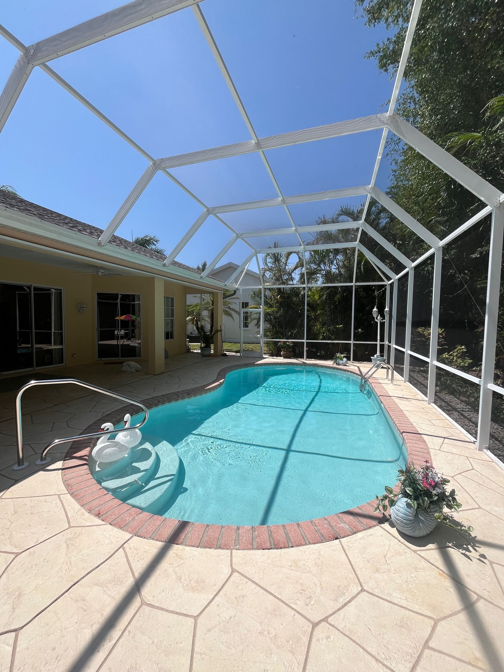A large swimming pool is surrounded by a screened in area