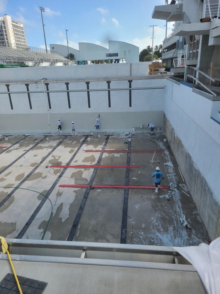 A swimming pool that is being remodeled with a few people working on it