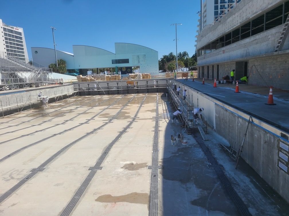 A swimming pool under construction with a building in the background
