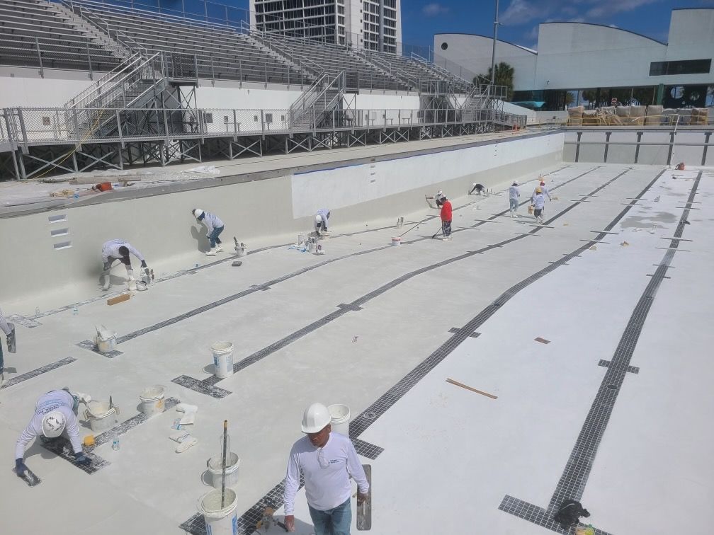 A group of construction workers are working on a swimming pool.