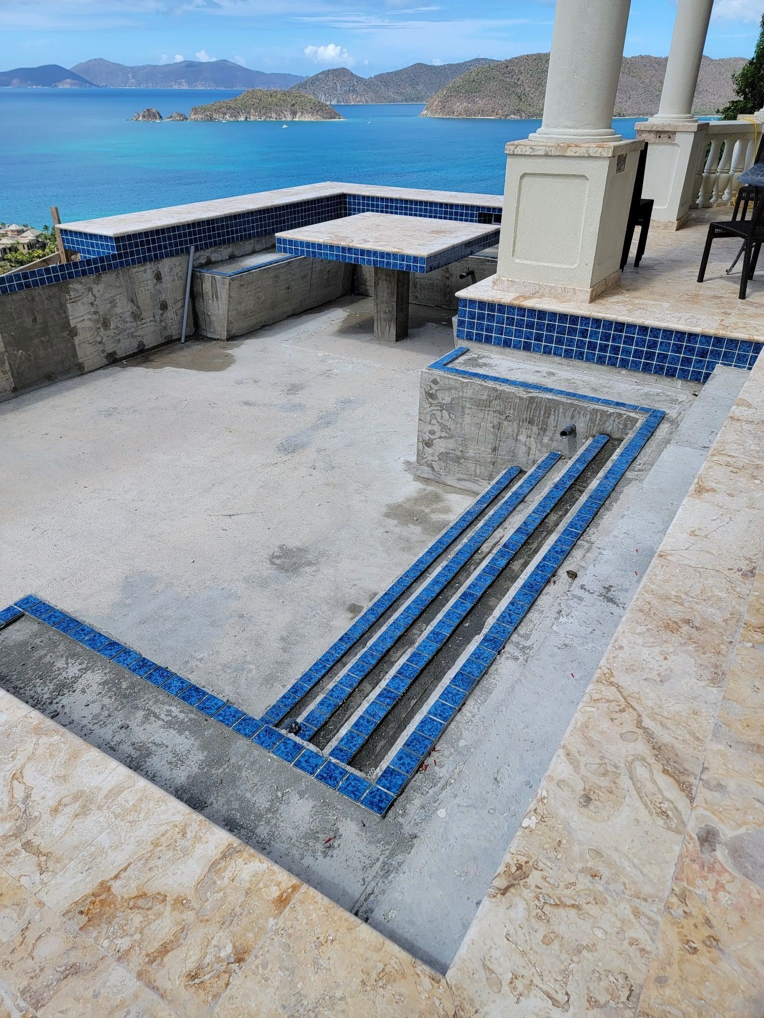 A patio with a table and chairs overlooking the ocean.