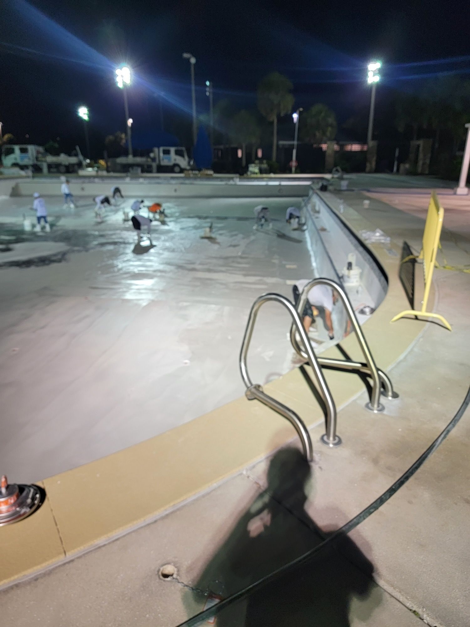 A man is standing next to a swimming pool at night