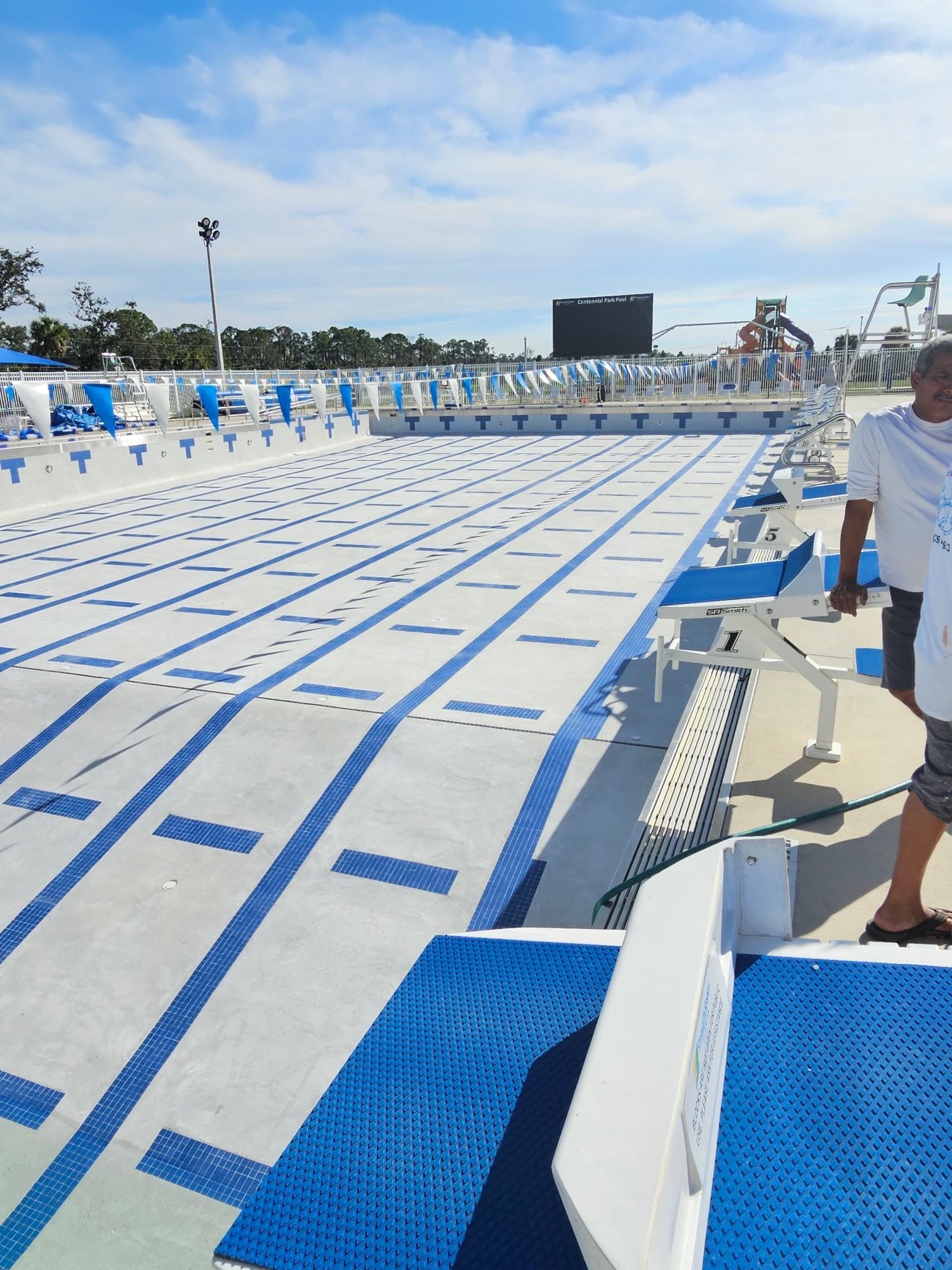 A man is standing in front of a large swimming pool