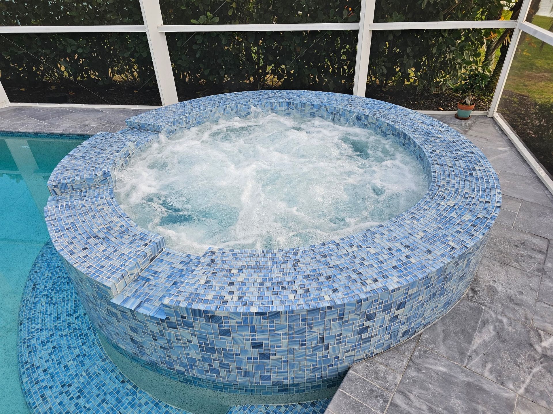 A round hot tub is sitting next to a swimming pool.