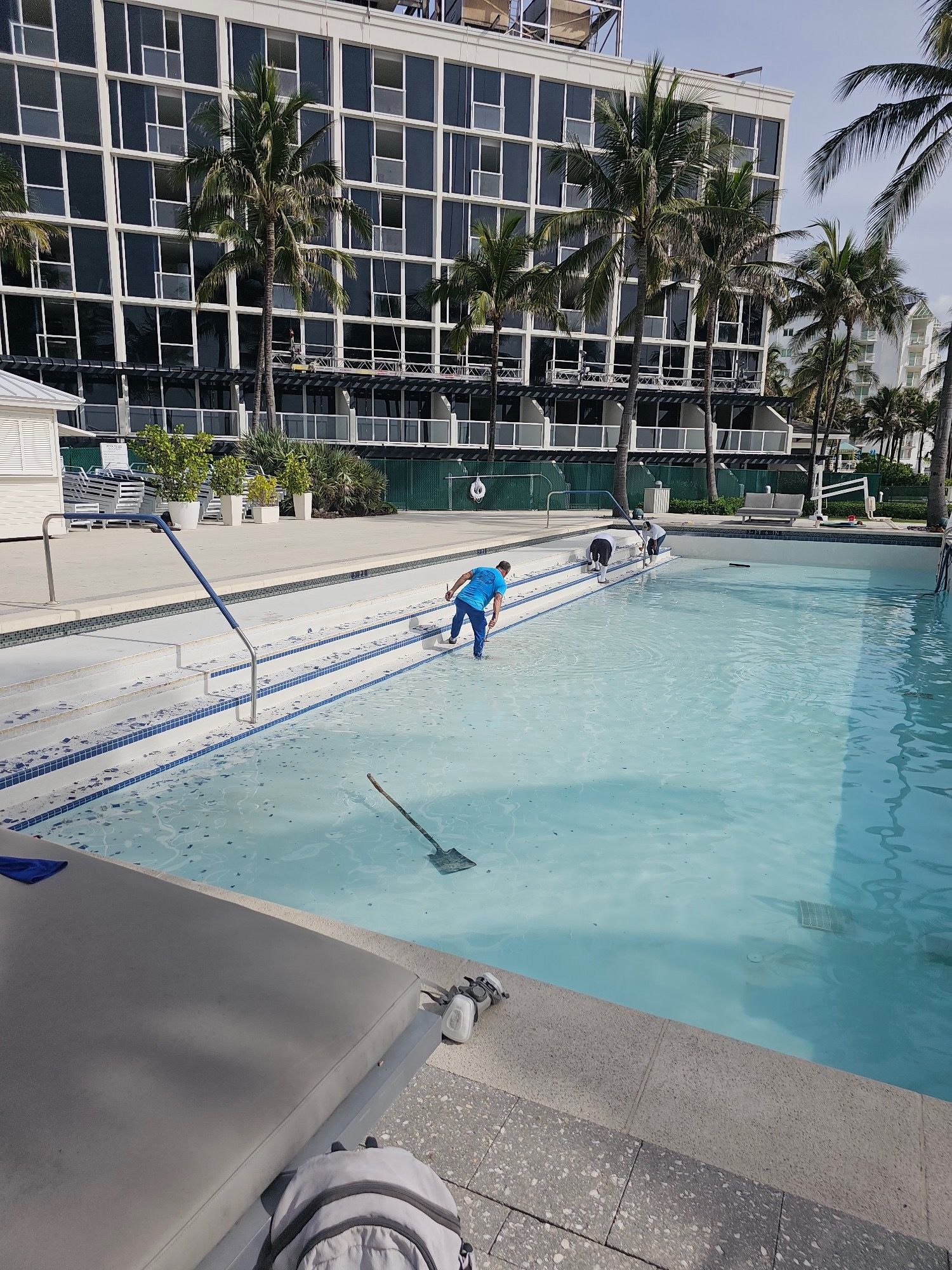 A man is cleaning a swimming pool in front of a building.