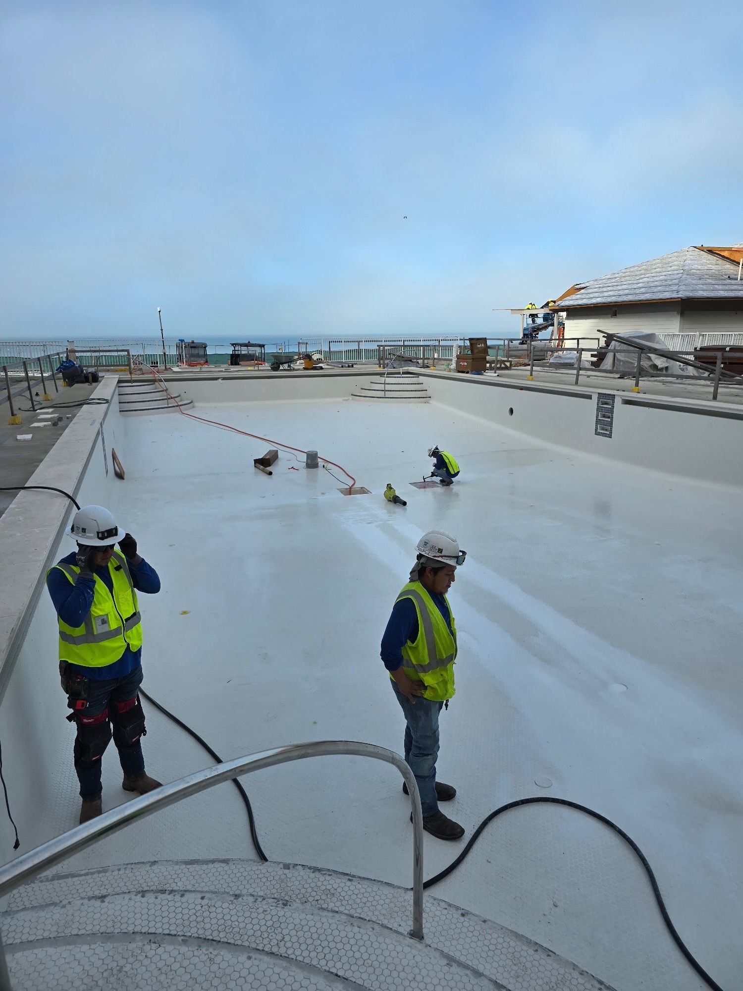 Two construction workers are working on a white roof