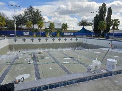 A large empty swimming pool is being painted.