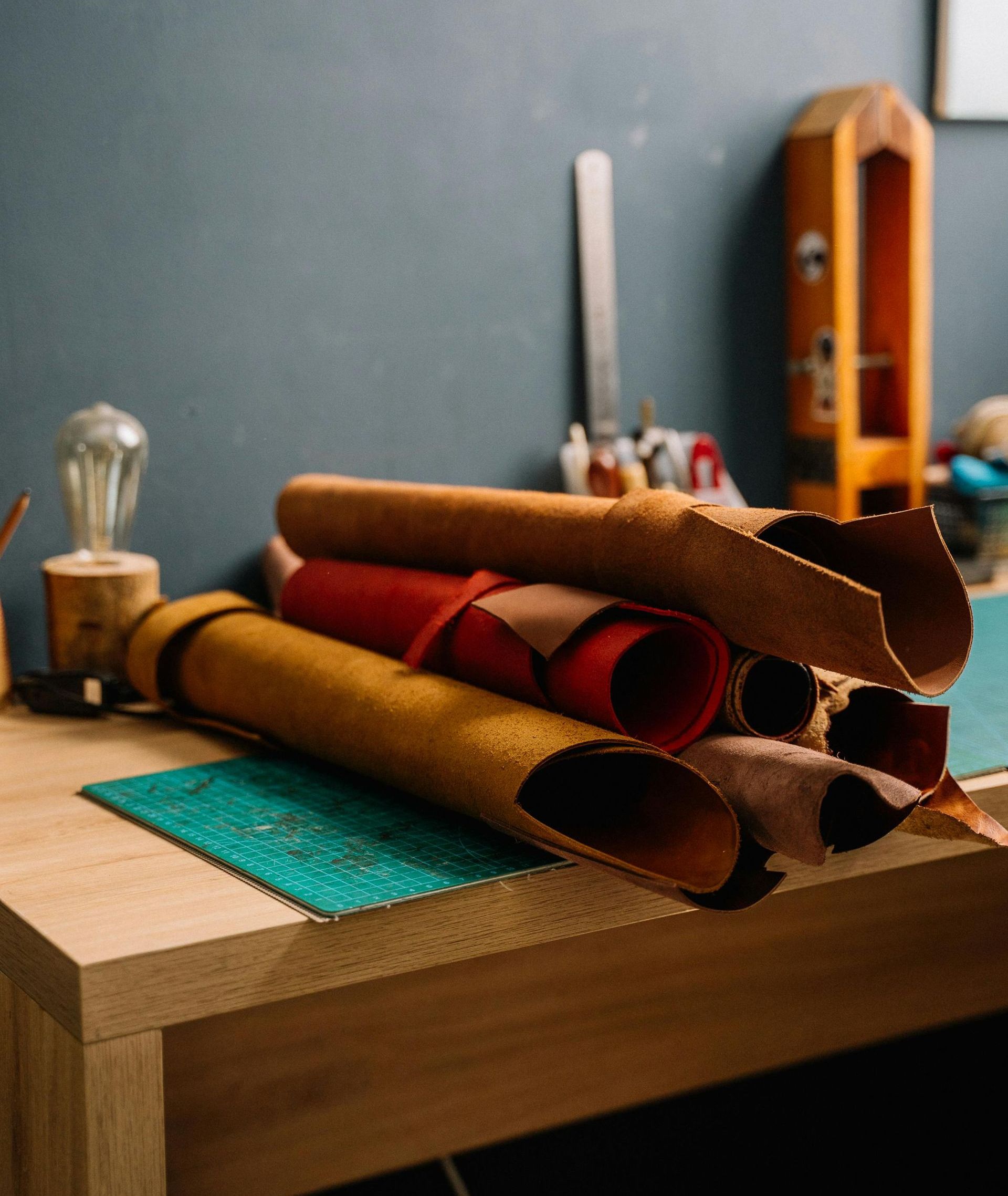 Rolls of leather on a work bench with leatherworking tools.