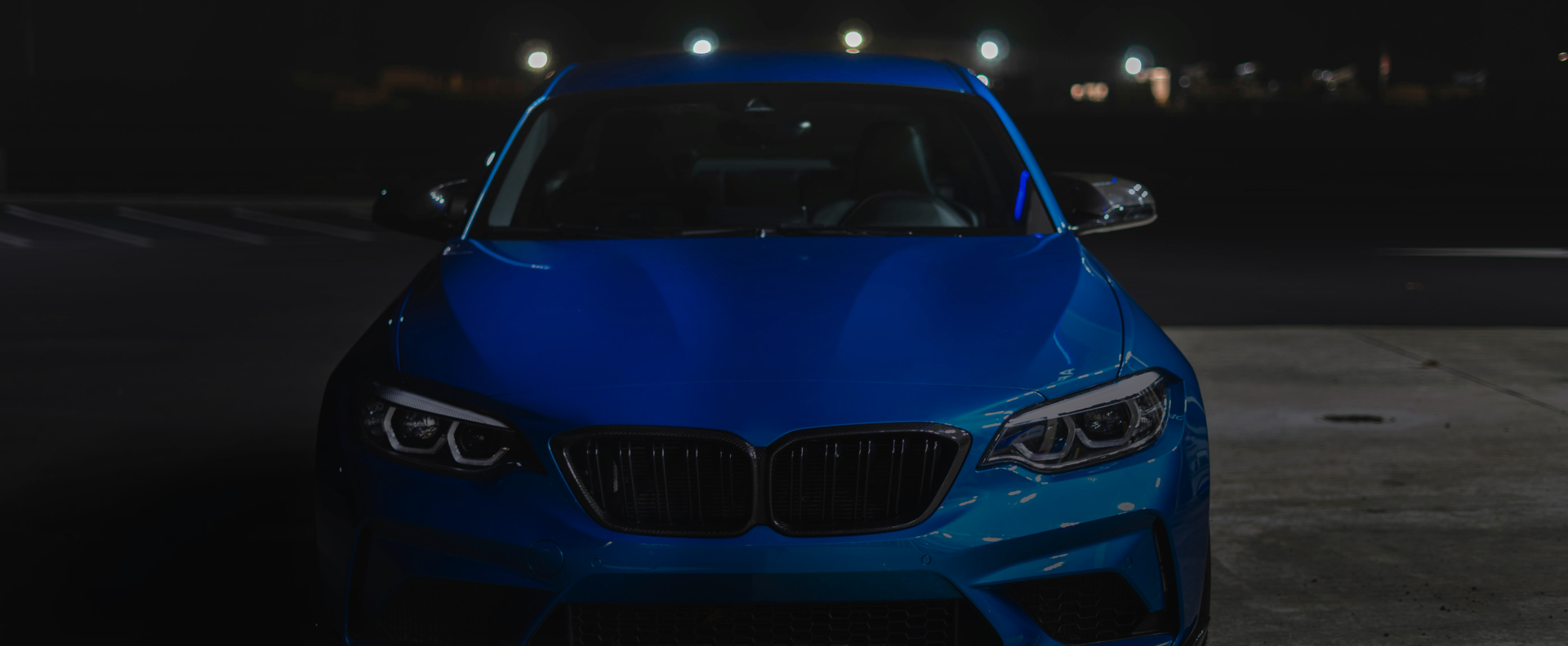 Blue BMW car parked at night, with headlights on - Bimmerfix