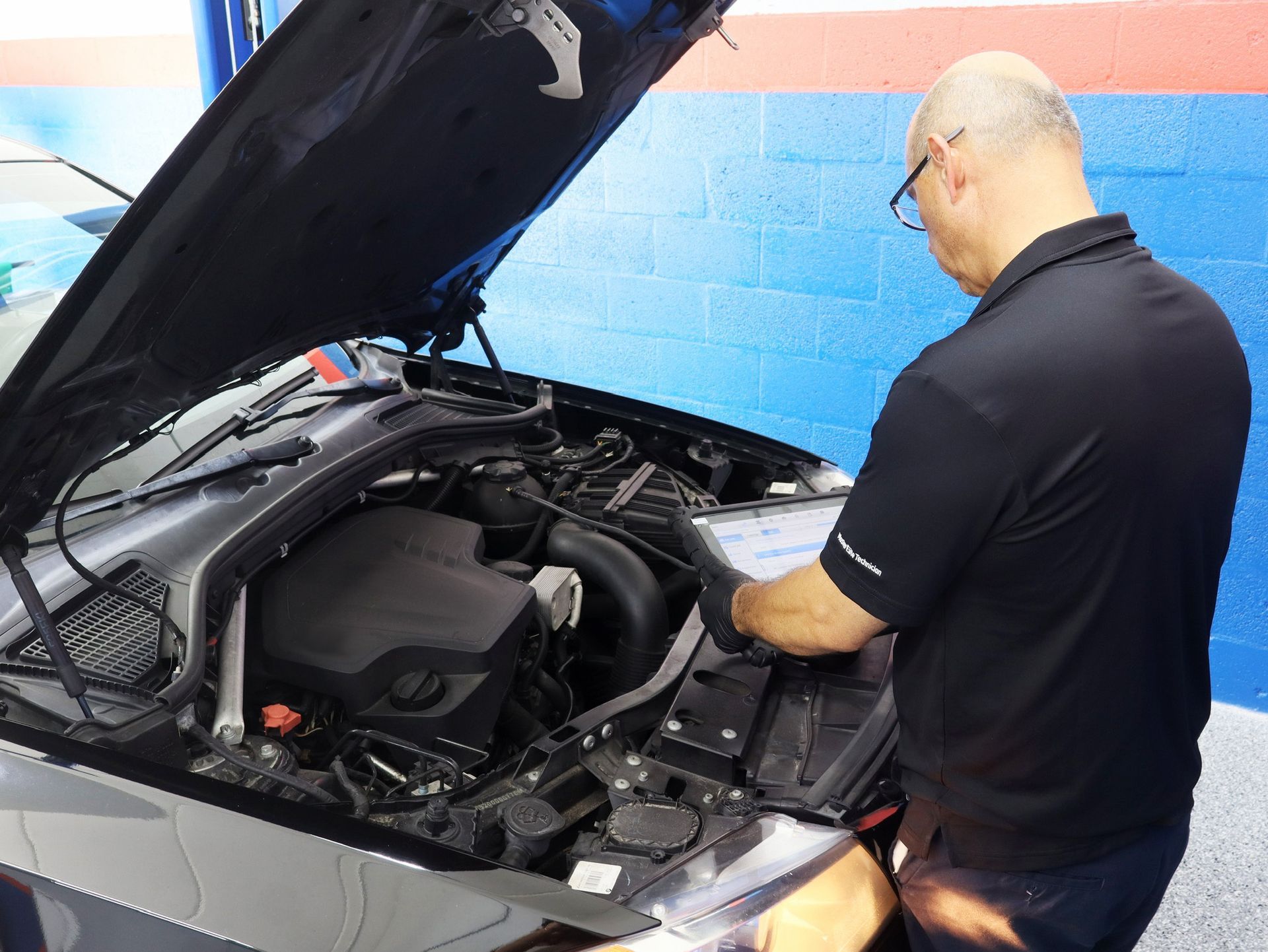 Mechanic working on car engine, open hood. | Bimmerfix