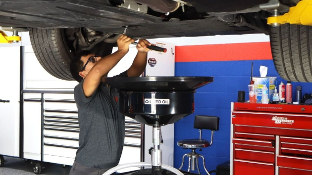 Mechanic draining oil from a car at a repair shop, using a drain pan - Bimmerfix