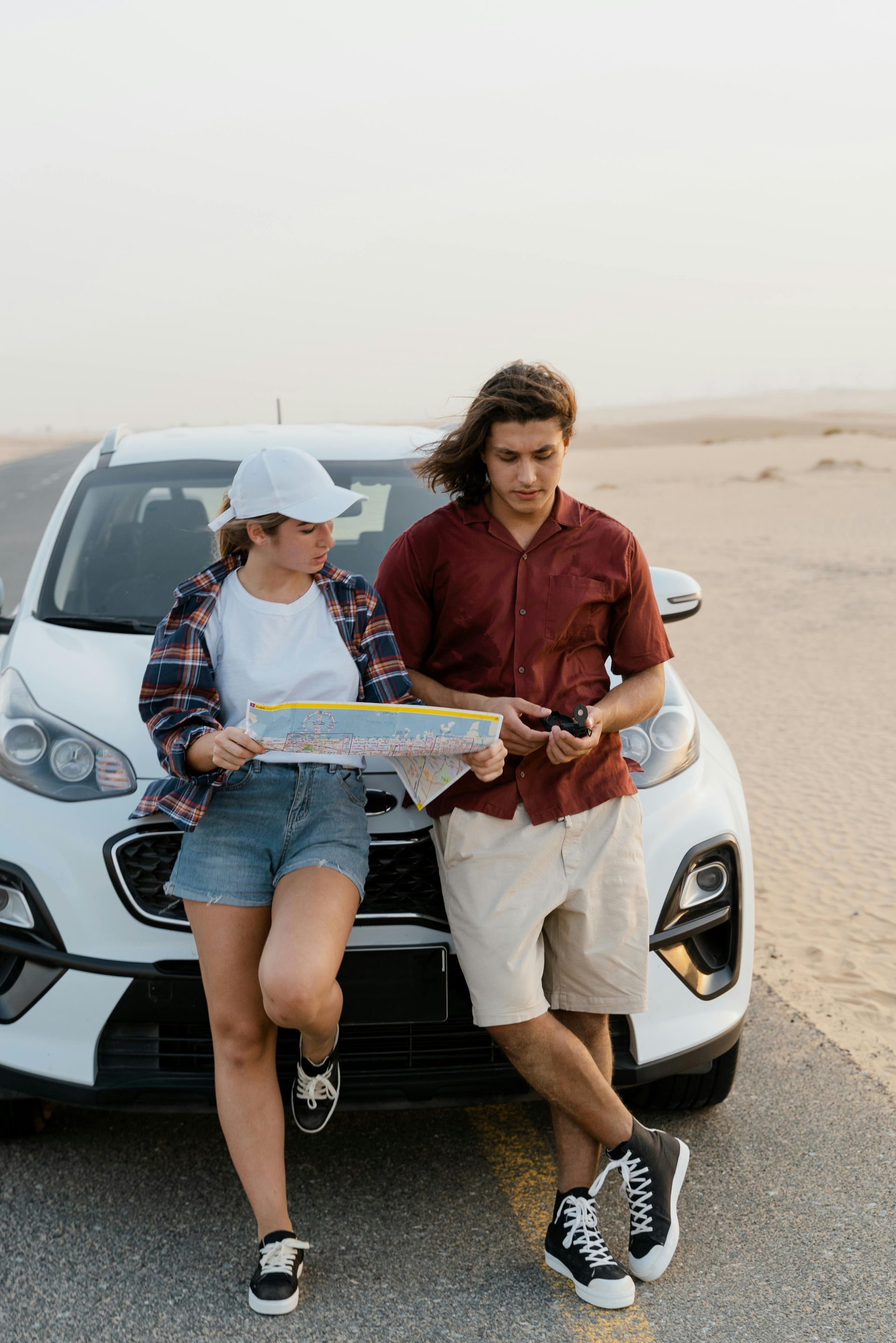 Two people leaning on a car reading a map on a road trip | Bimmerfix in Fort Myers, FL