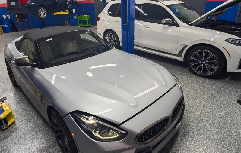 Silver BMW Z4 convertible and white BMW SUV in a garage - Bimmerfix