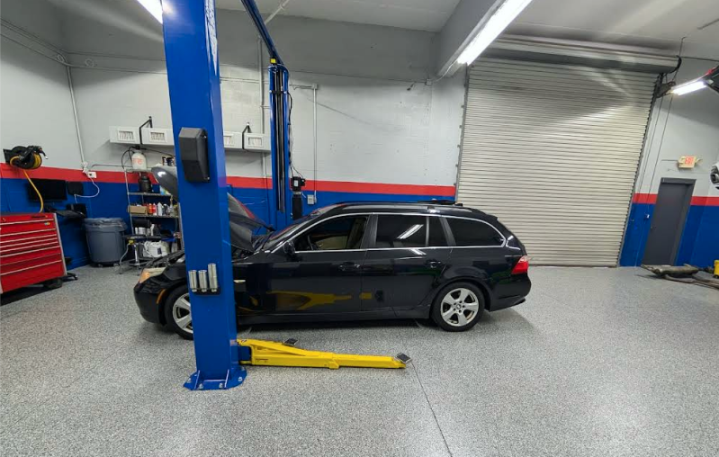 Black station wagon on a lift in a car repair shop - Bimmerfix