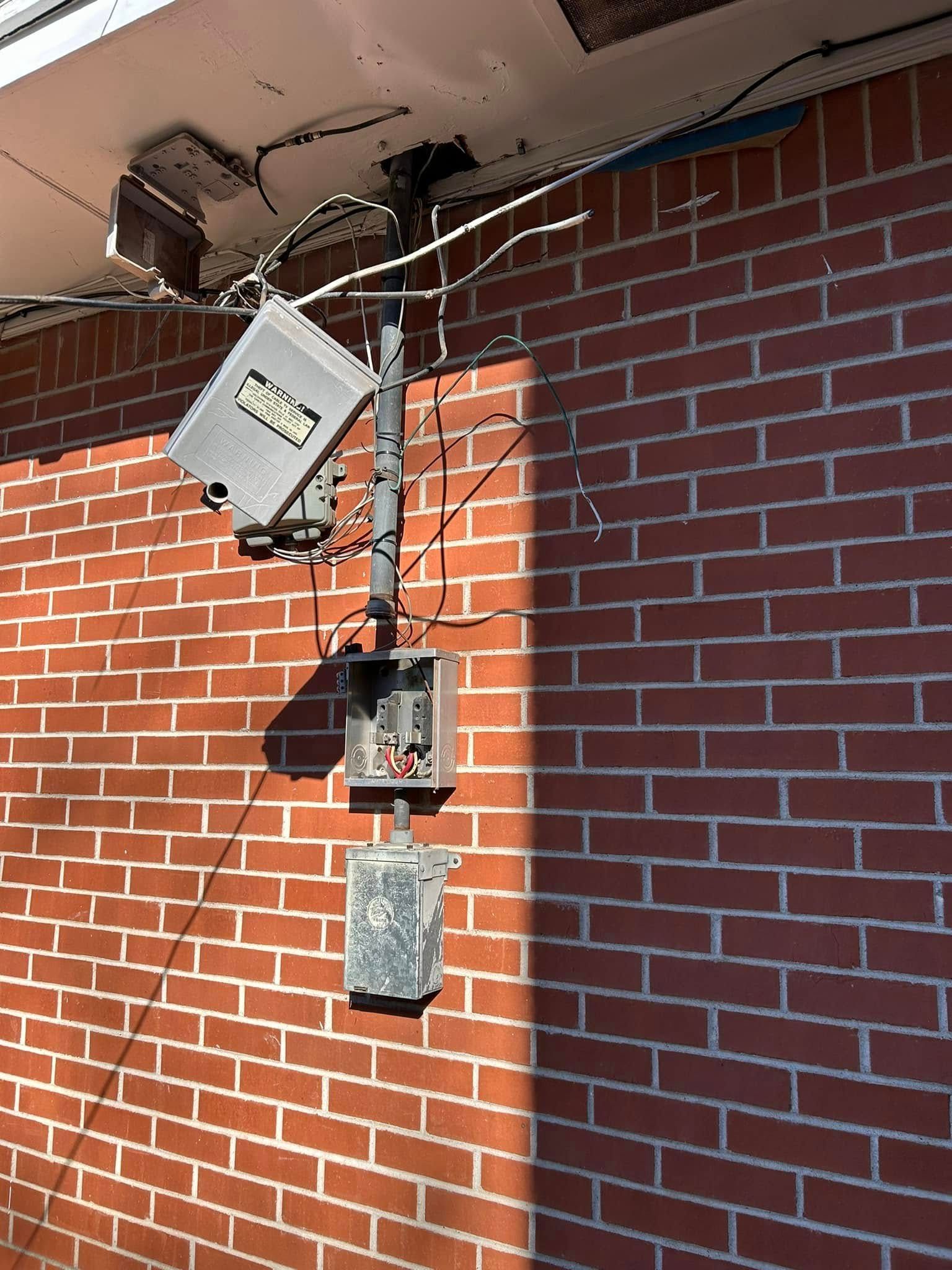 Brick wall with electrical boxes and wiring attached.
