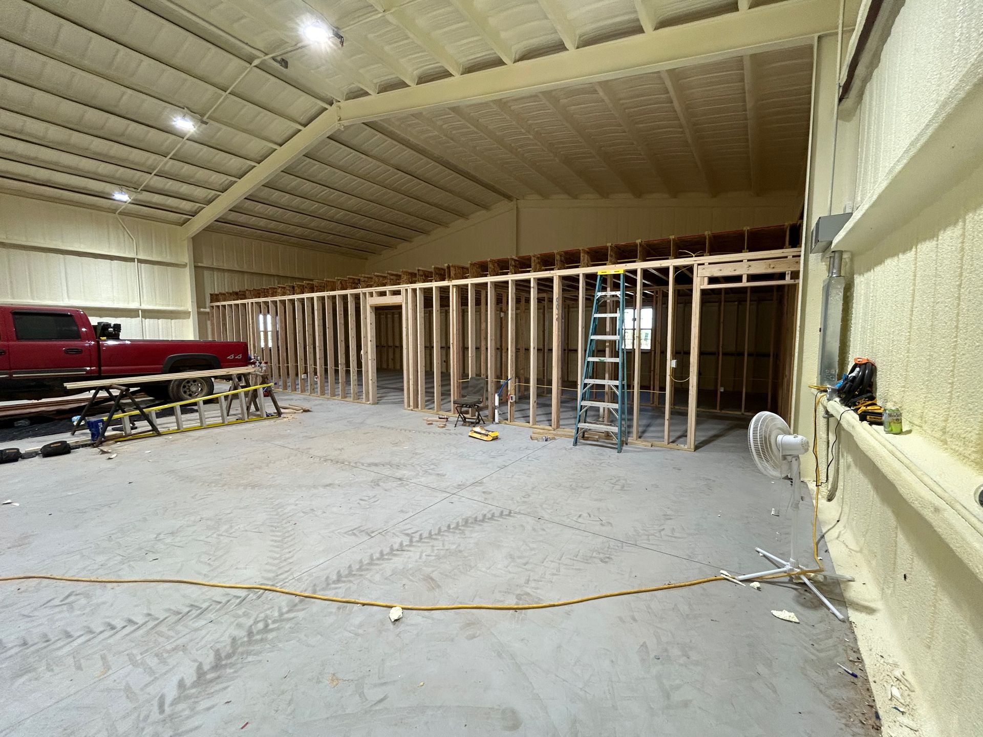 Interior of a commercial building under construction; wooden framing, spray foam insulation. A red truck is visible.