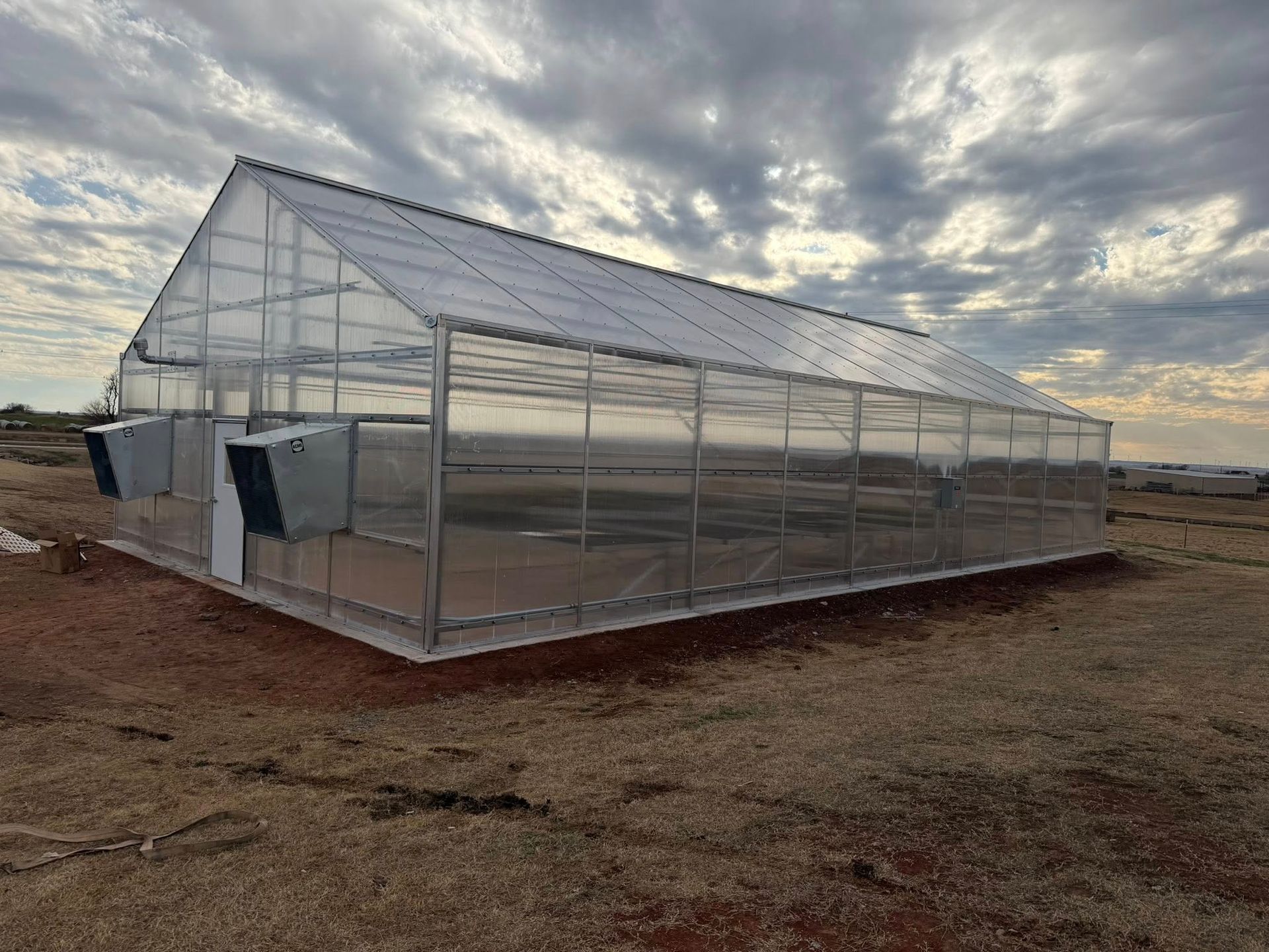 Greenhouse with clear panels under a cloudy sky.