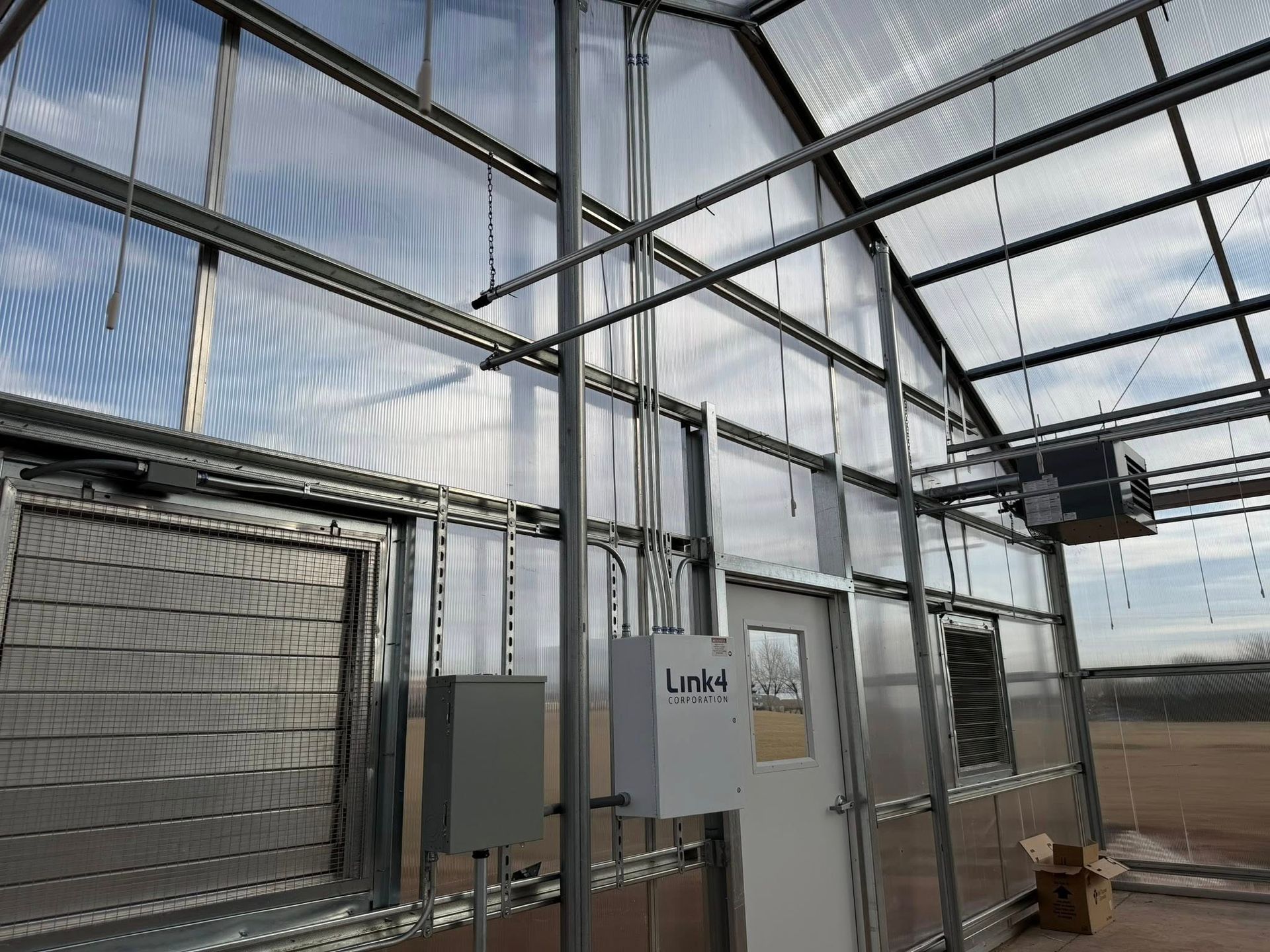 Interior of a greenhouse with metal framework and translucent panels.