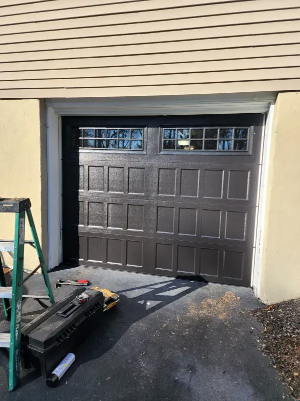 A garage door is being installed in front of a house.