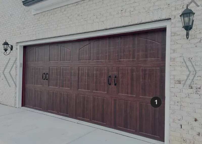 A large wooden garage door is on the side of a white brick building.