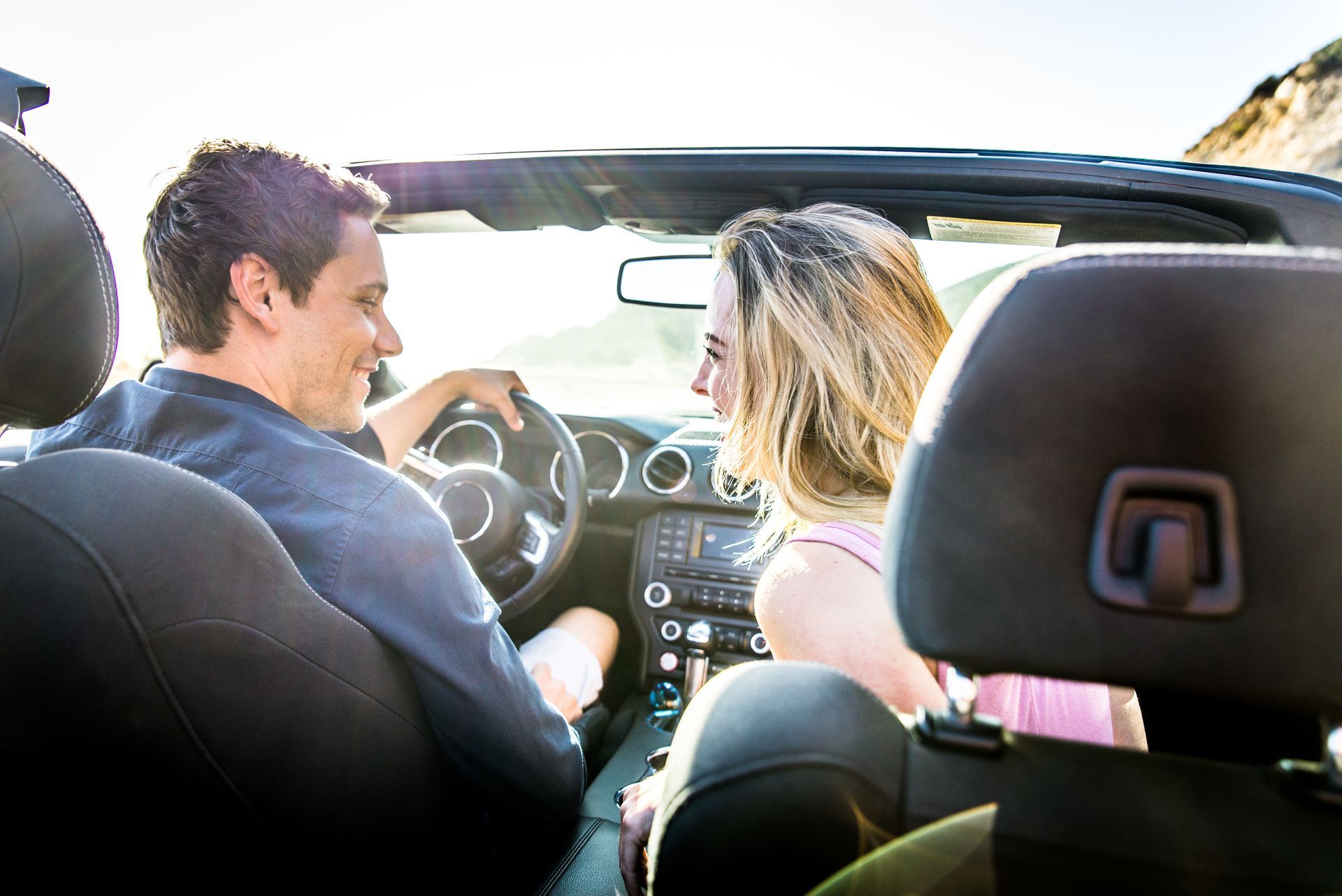 A man and a woman are sitting in a convertible car.