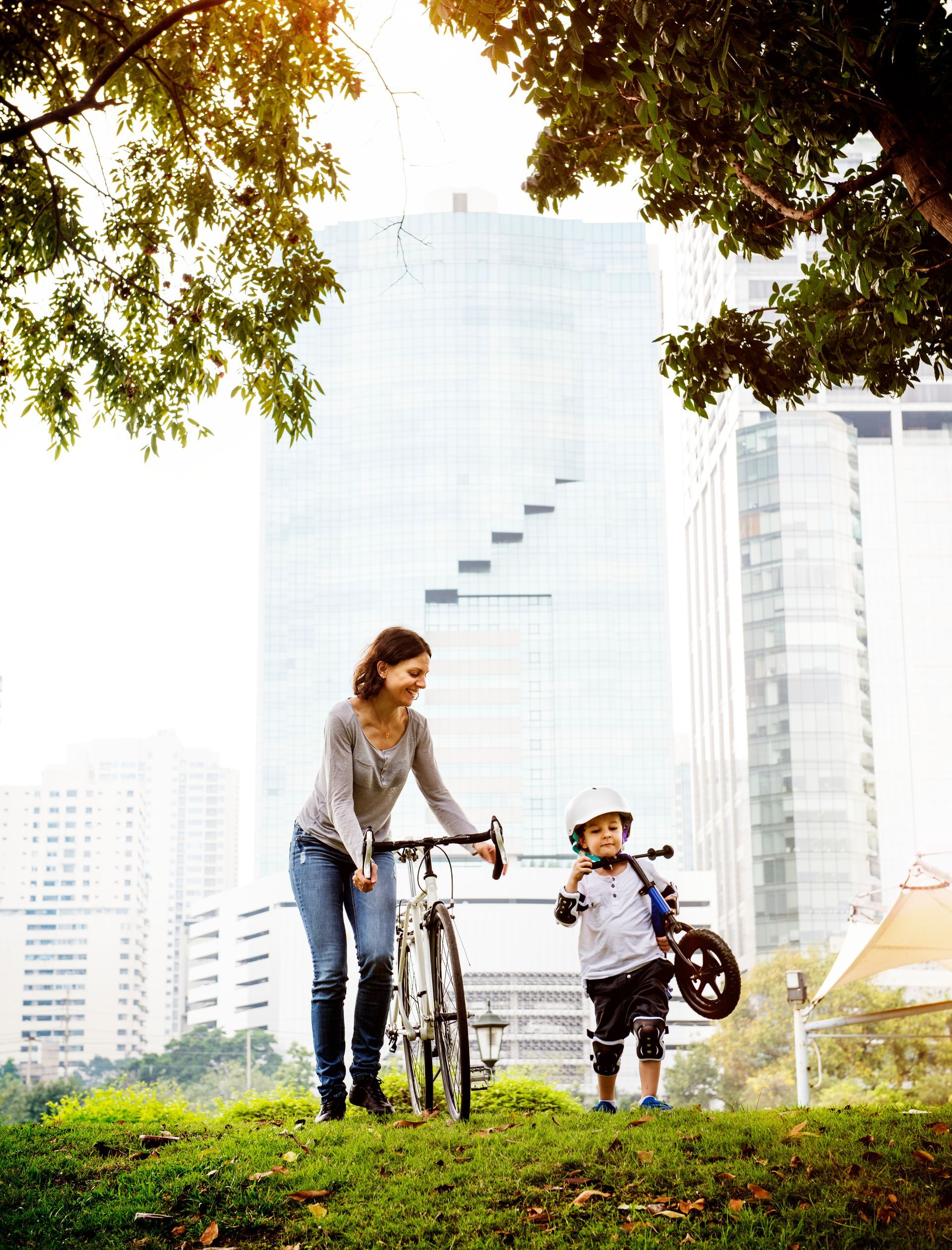 A woman is riding a bike next to a child who is holding a bike.