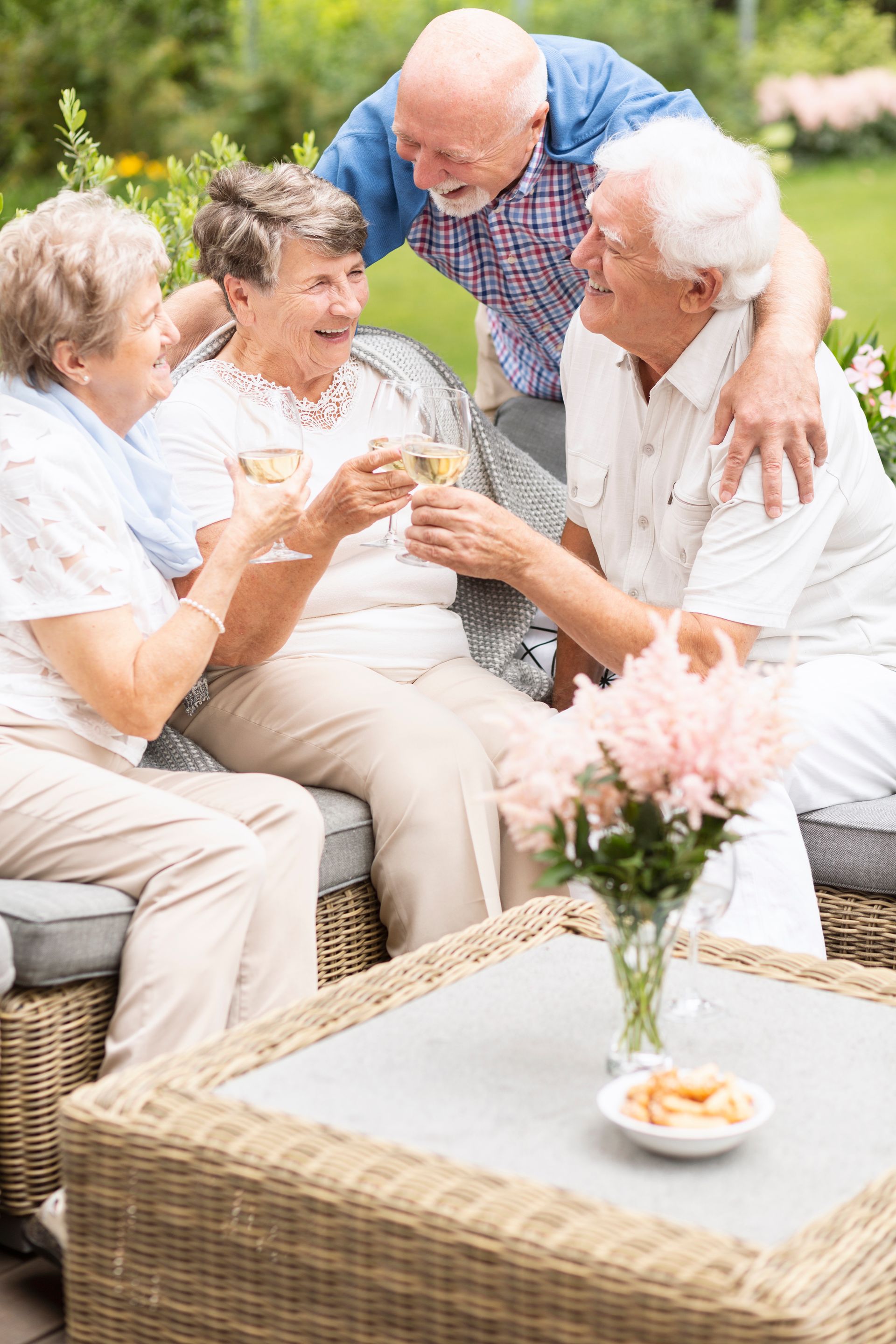 A group of elderly people are sitting on a couch drinking wine.