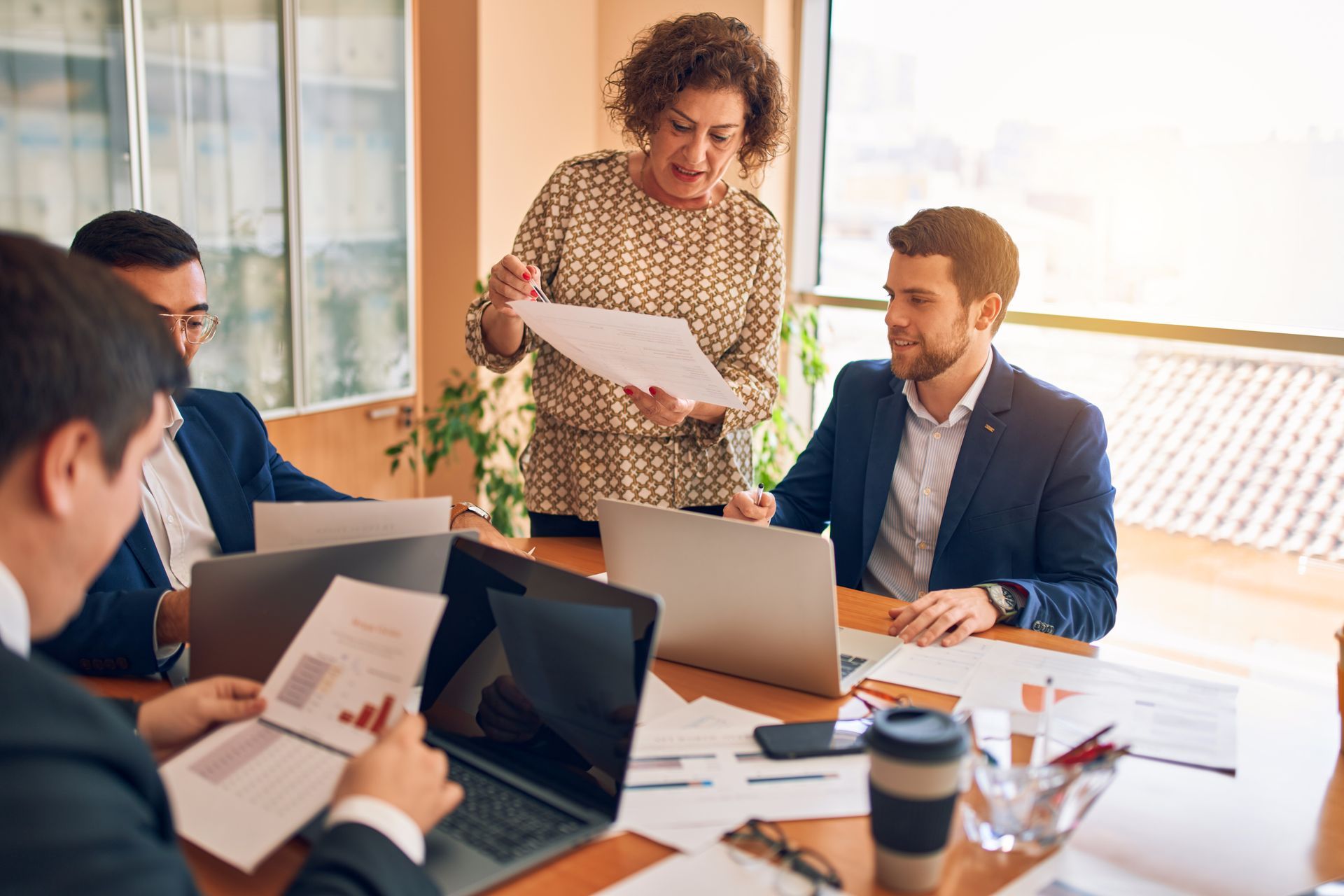 Business meeting: Woman presenting documents to colleagues around a table. Business meeting: Woman presenting documents to colleagues around a table.