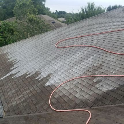 A roof is being cleaned with a hose.