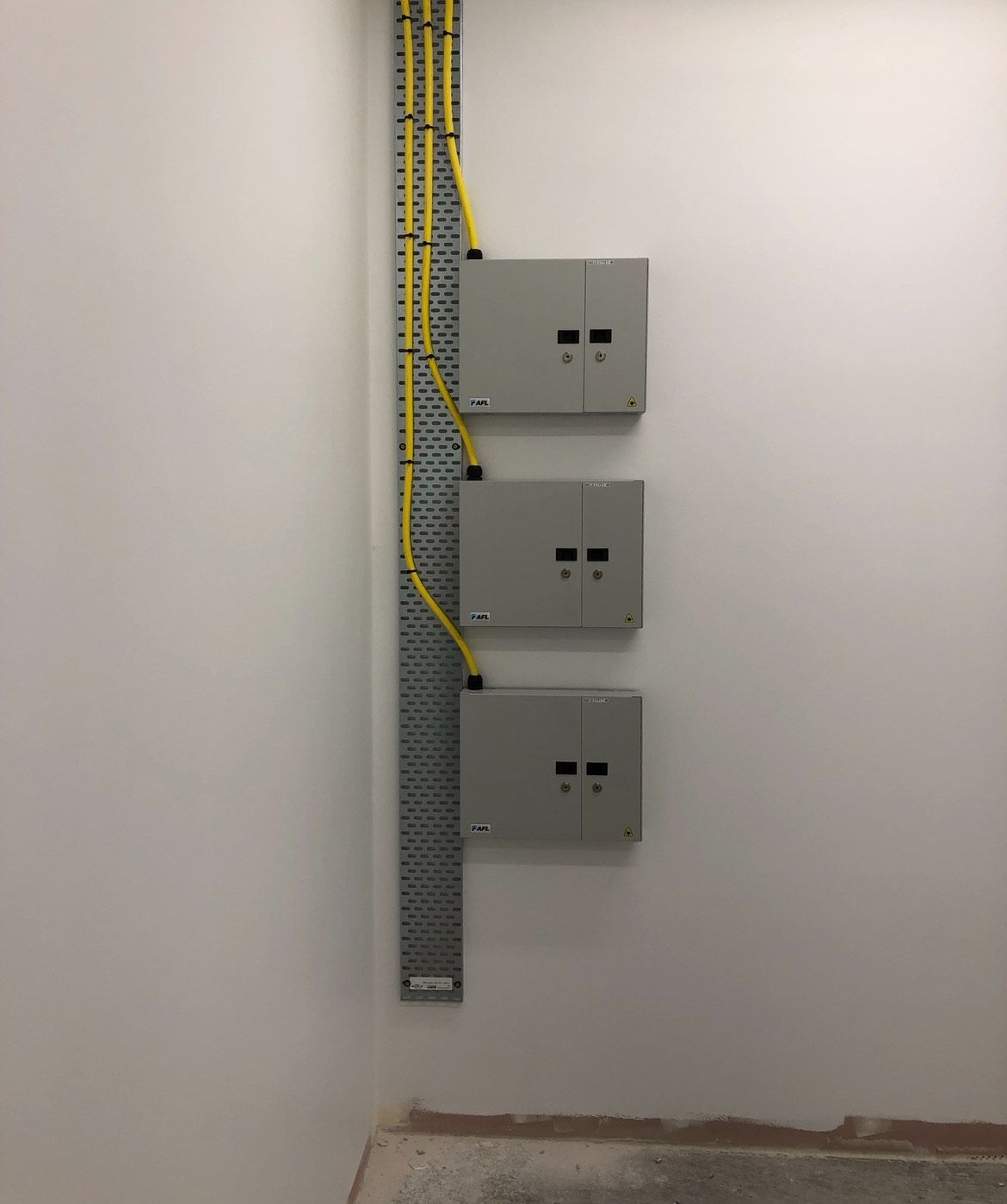 Three electrical boxes are hanging on a white wall
