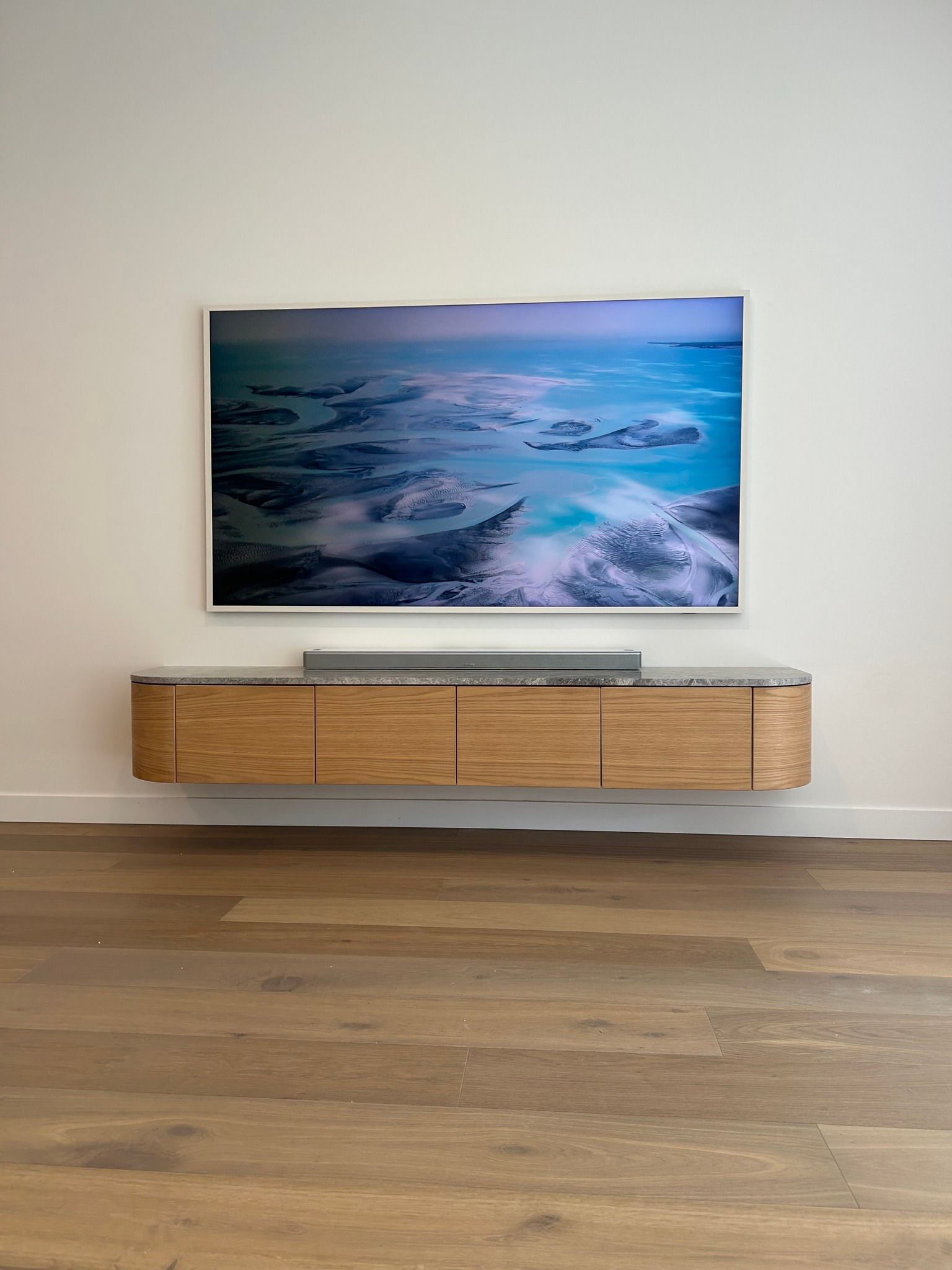 A flat screen tv is mounted on a wall above a wooden entertainment center.