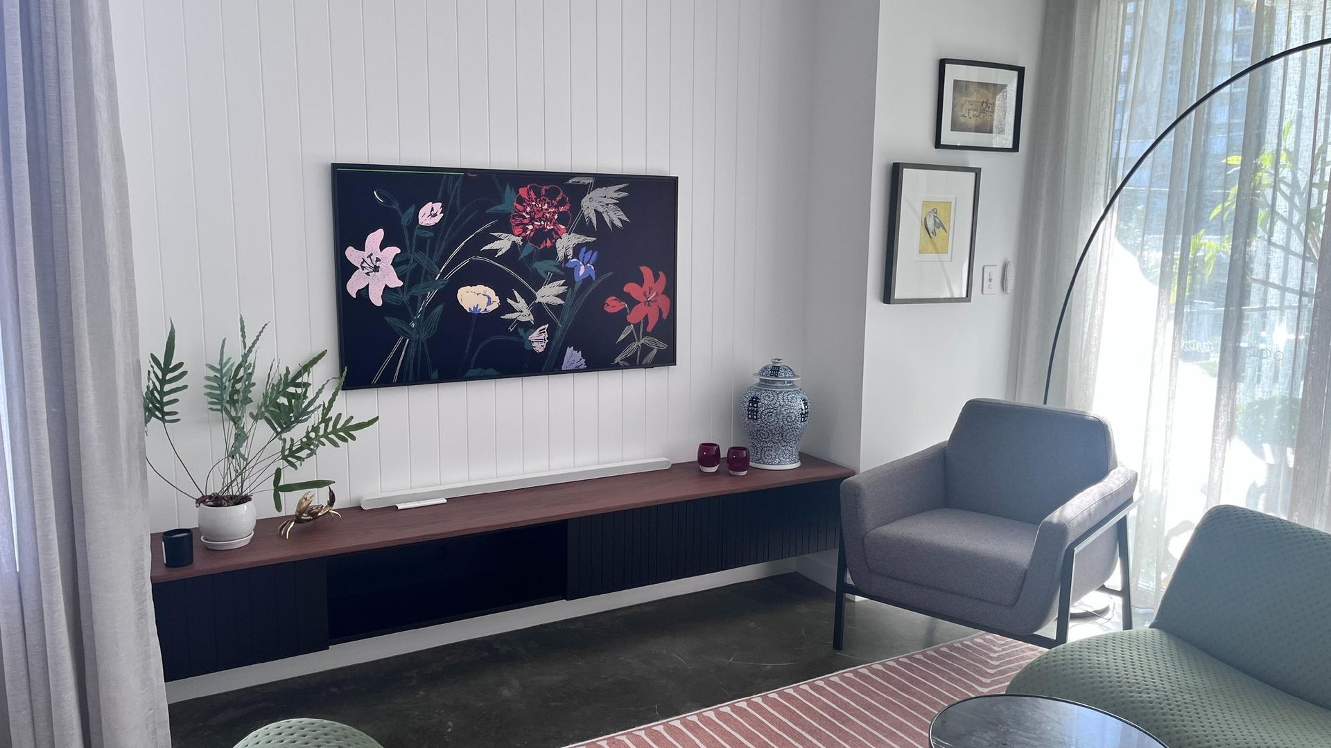 A living room with a couch , chair , table and a painting on the wall.