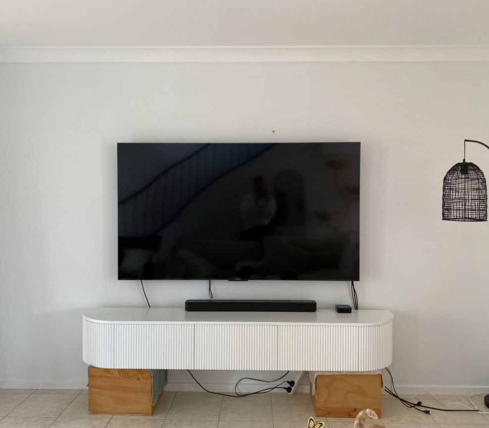 A flat screen tv is mounted to the wall above a white entertainment center.