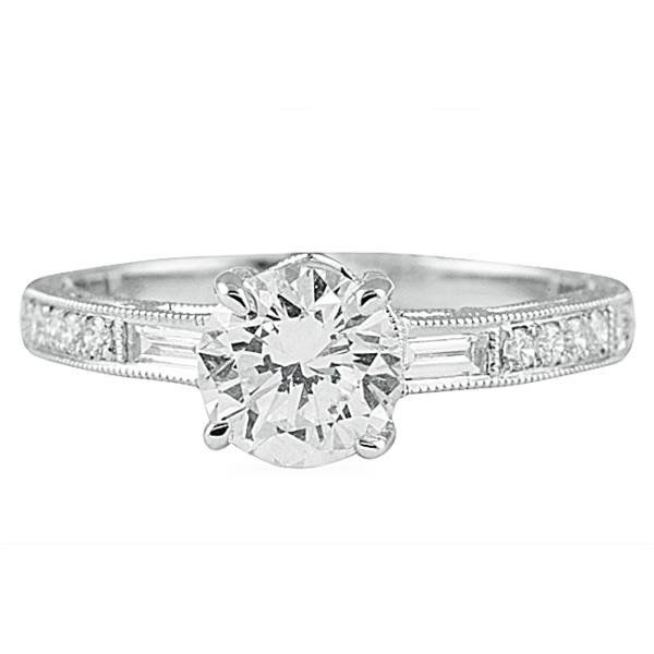 White gold engagement ring with round brilliant center diamond, baguette side stones, and milgrain edge detailing