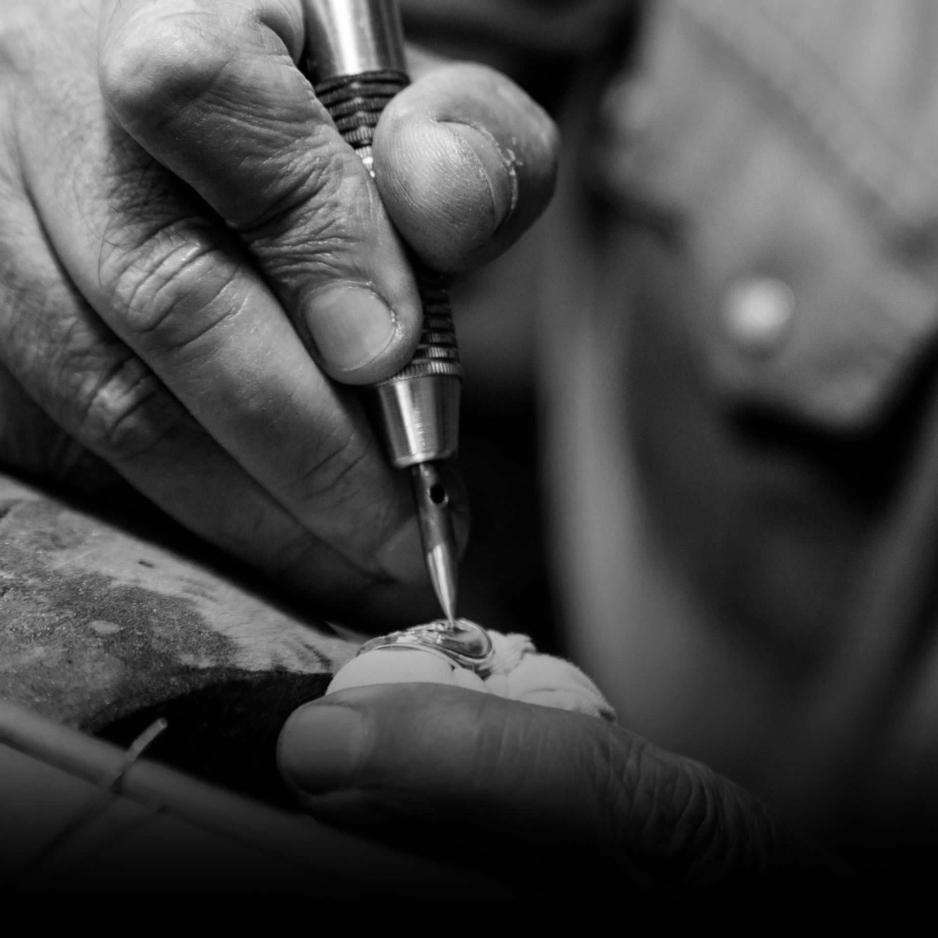 A black and white photo of a person using a tool on a piece of metal.