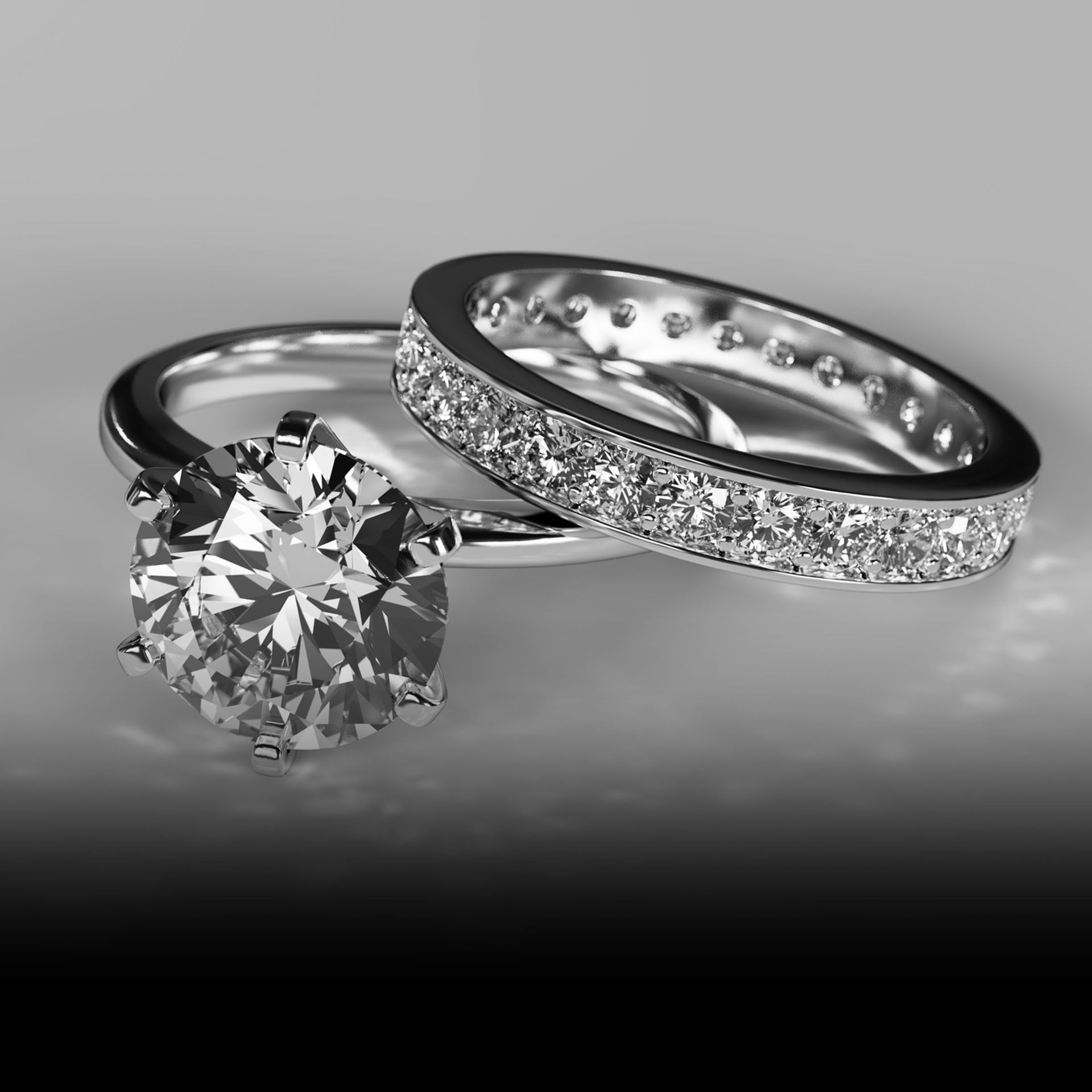 Pair of diamond rings with solitaire and pavé band on gray background