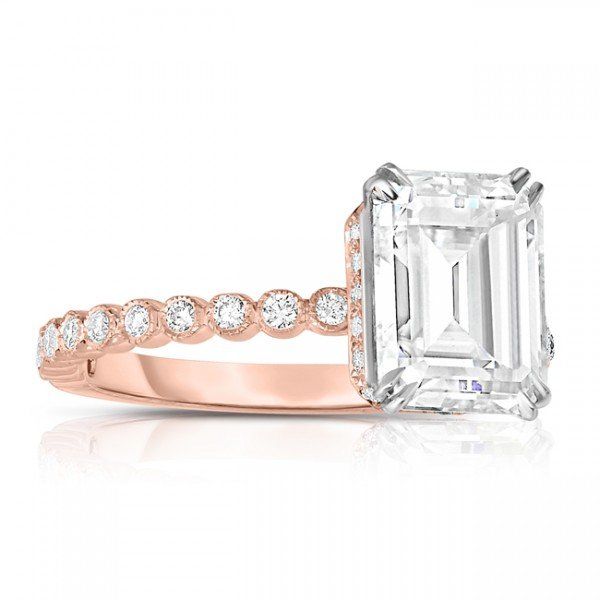 Rose gold engagement ring with an emerald-cut diamond and round diamond accents on the band