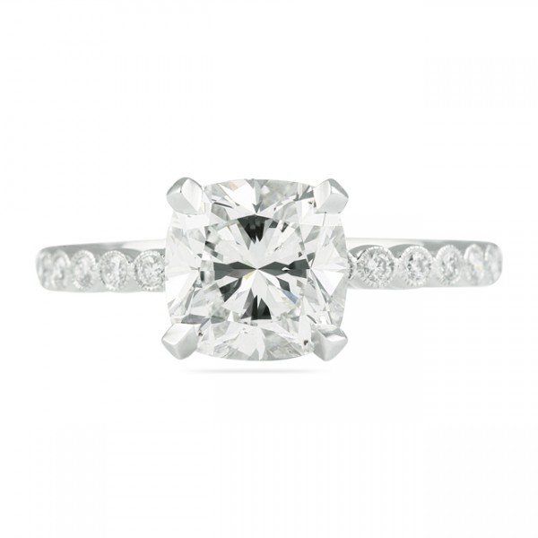 Cushion-cut diamond engagement ring with pave diamond band in white gold.