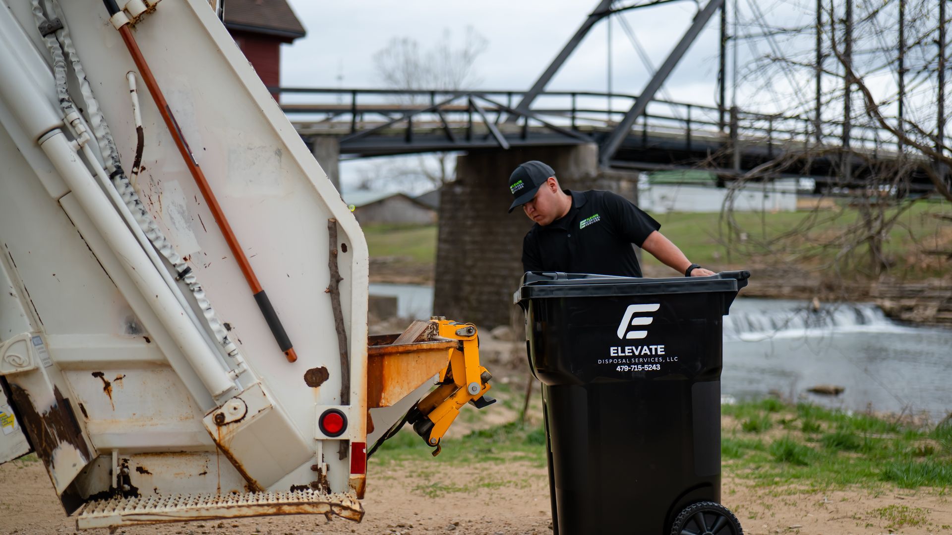 A blue dumpster filled with junk is sitting on the side of the road.
